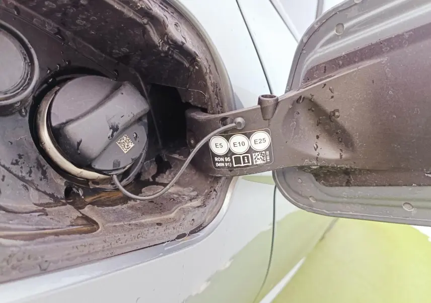 Gros plan sur la trappe à carburant ouverte d’une BMW Série 1 gris Skyscraper avec bouchon essence visible.