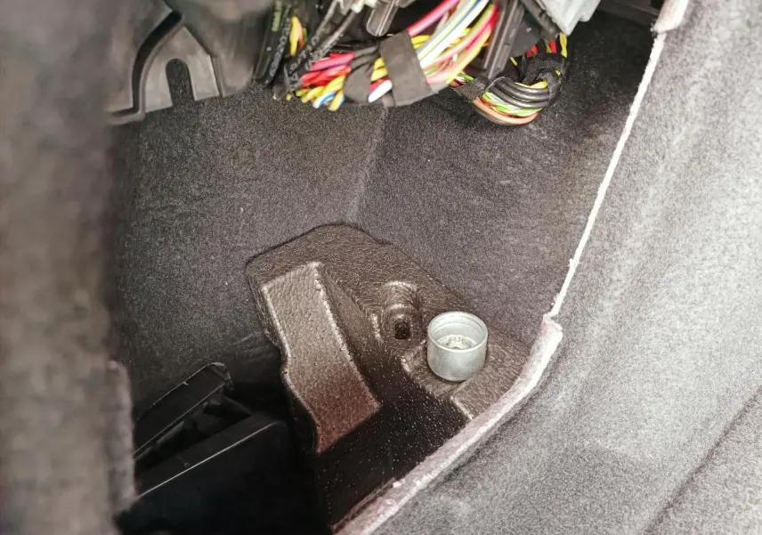 Gros plan sur l'intérieur du coffre de la BMW Série 1 F70 120 M Sport, montrant câblage et revêtement noir.