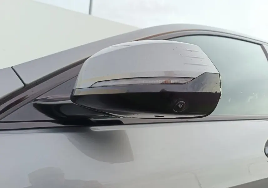 Gros plan sur le rétroviseur droit gris Skyscraper avec caméra intégrée sur BMW Série 1 2025 toit noir.