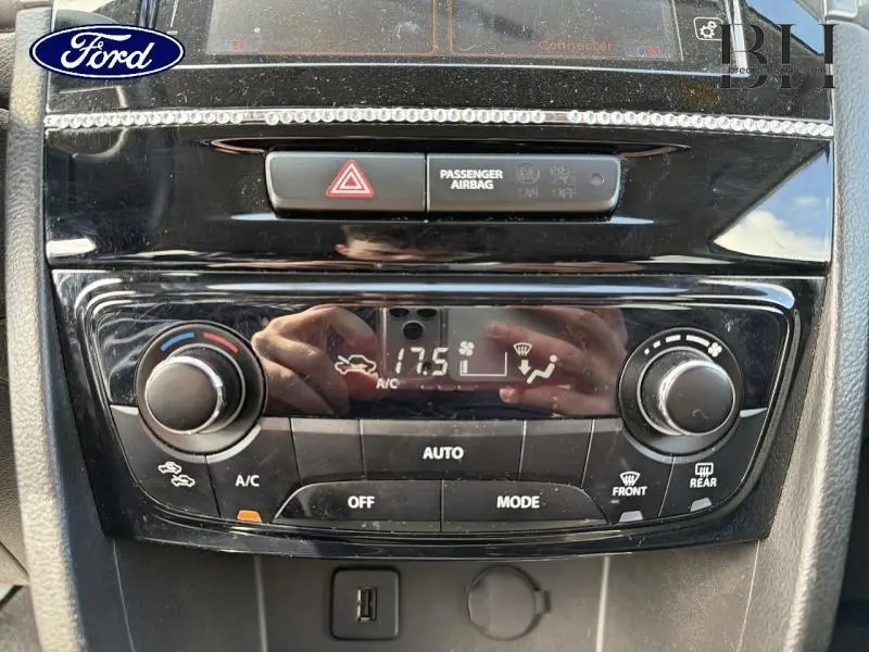 Tableau de bord noir brillant avec commandes de climatisation digitale et affichage à 17,5°C, intérieur Suzuki Vitara.