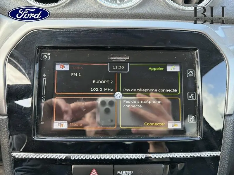 Vue rapprochée de l’écran tactile central noir du Suzuki Vitara Cosmic Black Pearl, affichant la radio FM et les options connectées.