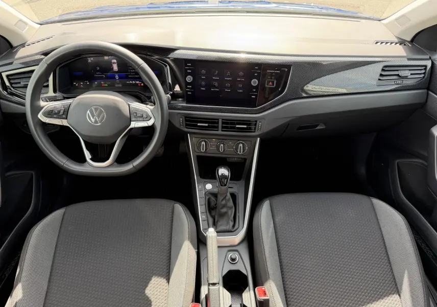Vue intérieure avant du Volkswagen Taigo 2025 avec tableau de bord noir, volant cuir multifonctions et console centrale compacte.