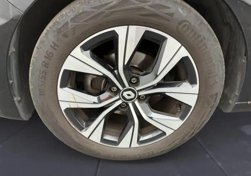 Gros plan sur la roue avant droite d'une Renault Clio noire 2023, avec jante alliage au design moderne.