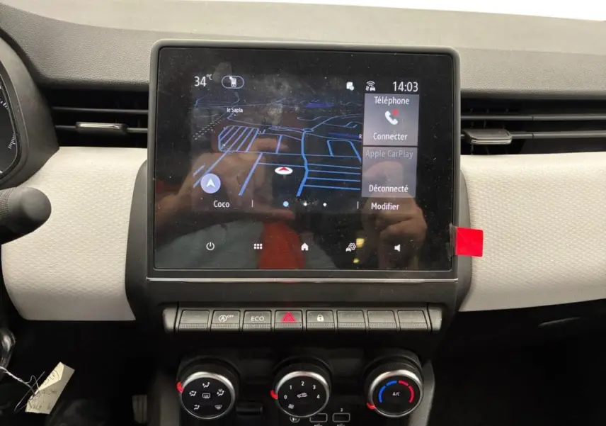 Vue rapprochée du tableau de bord de la Renault Clio noire 2023, avec écran tactile et commandes manuelles de climatisation.