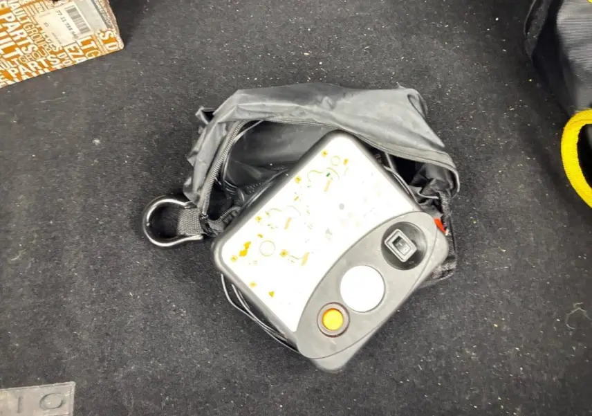 Sac noir avec compresseur de pneu posé sur le tapis de coffre d’une Renault Clio V TCe 100 GPL noir 2023.