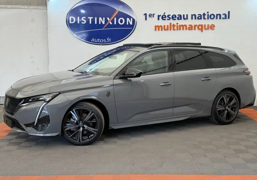 Profil côté gauche d'une Peugeot 308 Hybrid 136 e-DCS6 GT gris foncé avec jantes noires et vitres teintées en showroom.