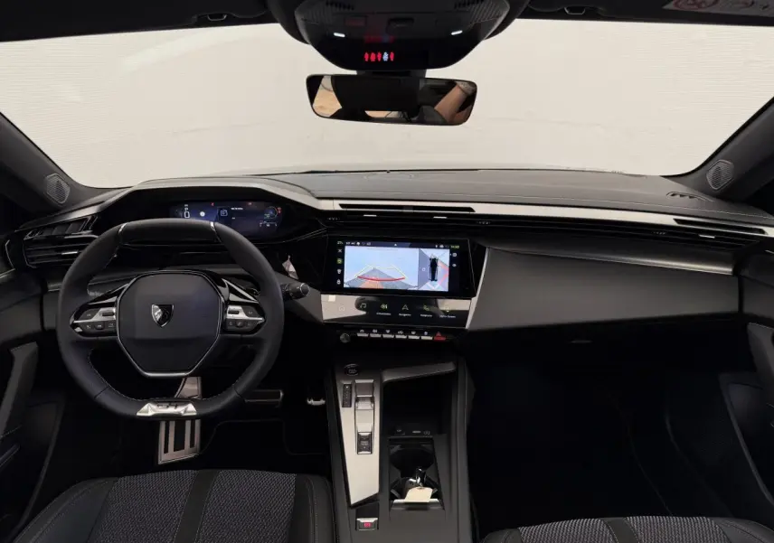 Intérieur noir de la Peugeot 308 Hybrid 136 e-DCS6 GT 2024, vue frontale du tableau de bord et volant multifonctions.