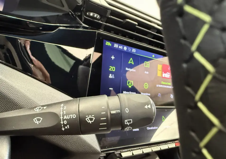 Gros plan sur la commande d’essuie-glace et l’écran tactile du tableau de bord d’une Peugeot 308 Hybrid gris foncé.