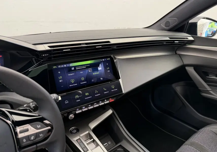 Intérieur avant droit de la Peugeot 308 Hybrid 136 e-DCS6 GT 2024, tableau de bord moderne gris foncé avec écran tactile central.