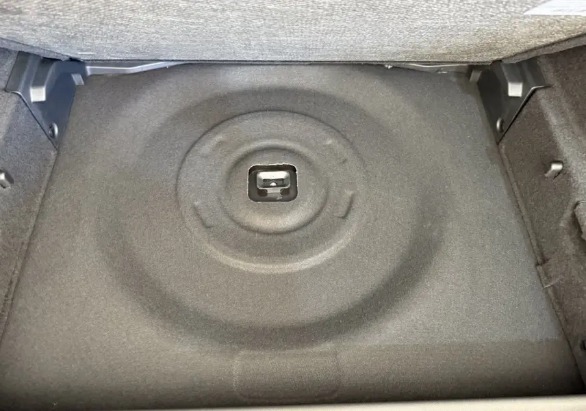 Coffre ouvert de la Peugeot 308 Hybrid 136 e-DCS6 GT 2024, vue intérieure sur le rangement sous plancher gris foncé.