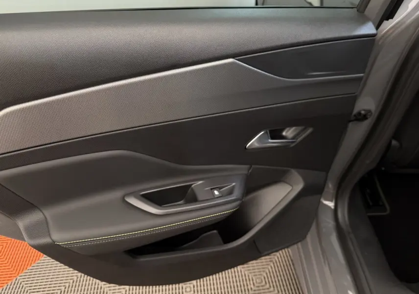 Gros plan sur la porte arrière droite grise du Peugeot 308 Hybrid 136 e-DCS6 GT avec surpiqûres vertes visibles.