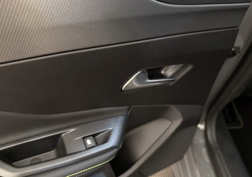 Gros plan sur la porte côté conducteur gris foncé de la Peugeot 308 Hybrid 136 e-DCS6 GT avec poignée et bouton de verrouillage.