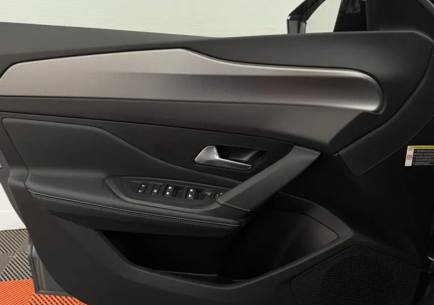 Gros plan sur la porte côté conducteur de la Peugeot 308 Hybrid gris foncé, avec commandes électriques et finition cuir noire.