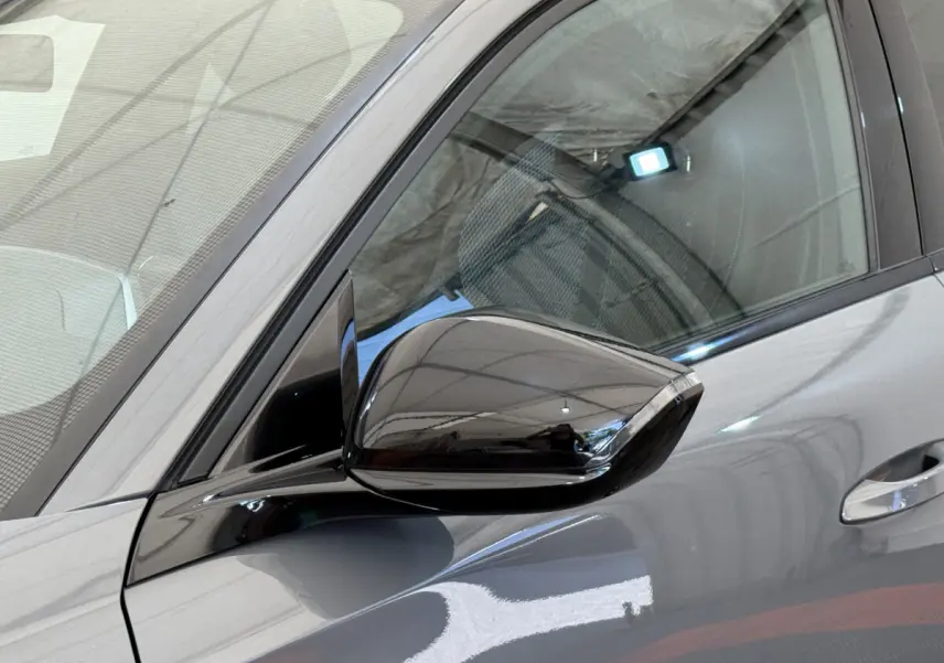 Gros plan sur le rétroviseur côté gauche d'une Peugeot 308 Hybrid 136 e-DCS6 GT gris foncé avec carrosserie brillante.