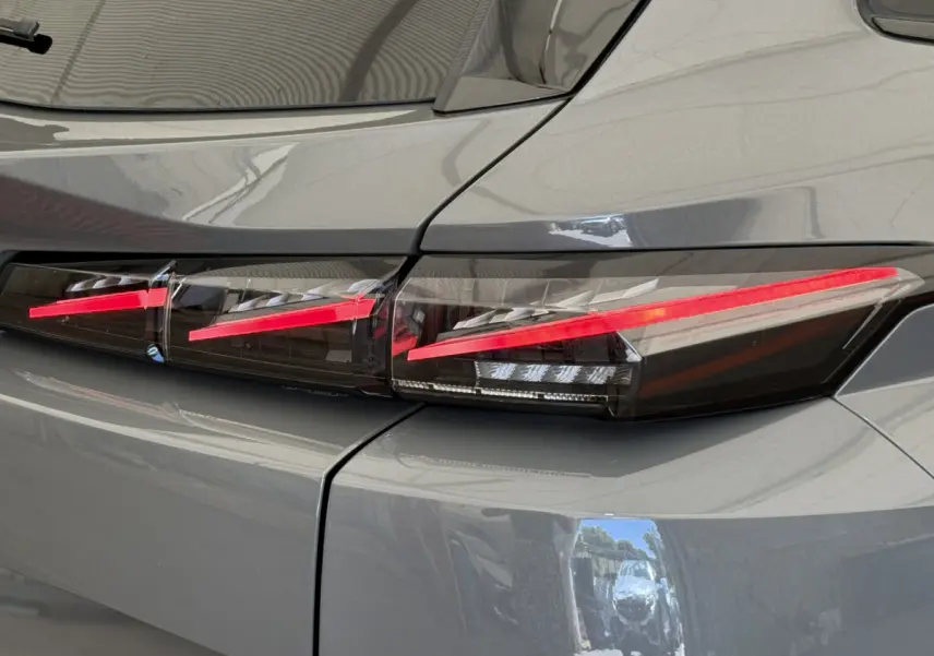 Gros plan sur le feu arrière droit rouge vif d'une Peugeot 308 Hybrid 136 e-DCS6 GT gris foncé 2024.