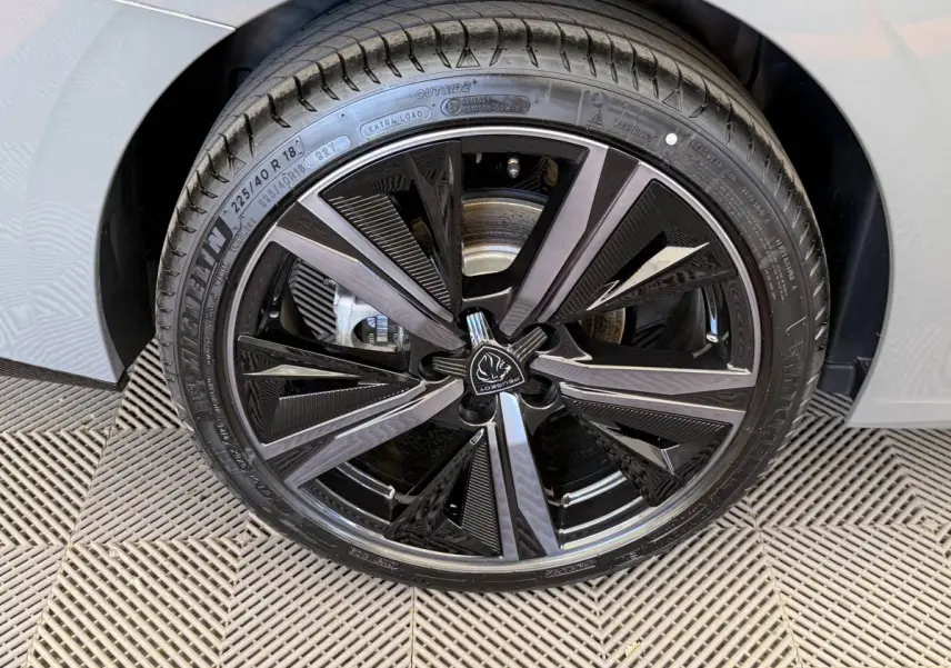 Gros plan sur la jante noire et argentée du côté gauche d'une Peugeot 308 Hybrid 136 e-DCS6 GT gris foncé.