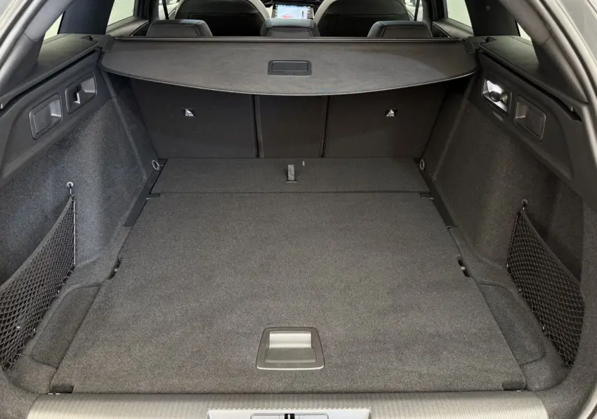 Coffre spacieux de la Peugeot 308 Hybrid gris foncé vu de l'arrière avec banquette rabattue et filet de rangement.