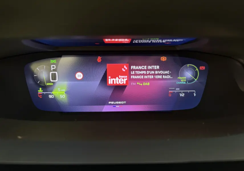 Affichage numérique 10 pouces du combiné instruments de la Peugeot 308 Hybrid 136 e-DCS6 GT, avec radio France Inter allumée.