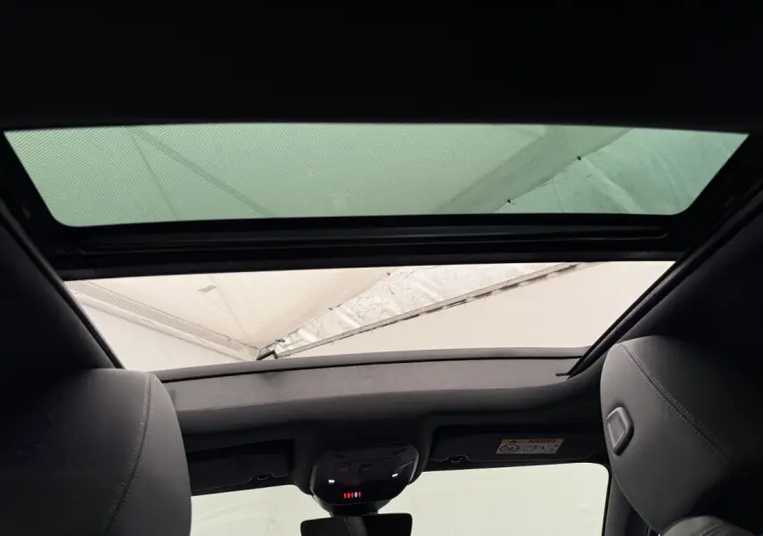 Vue intérieure du toit ouvrant panoramique de la Peugeot 308 Hybrid 136 e-DCS6 GT gris foncé, avec ciel visible à travers le verre.