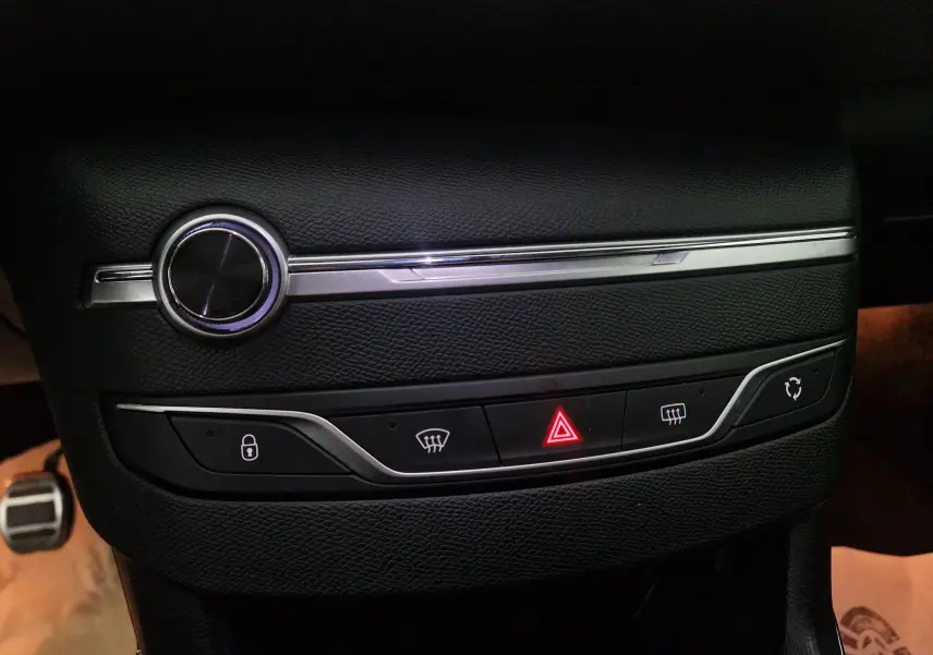 Détail du tableau de bord noir avec commandes de verrouillage, dégivrage et warning allumé sur Peugeot 308 SW gris Artense.