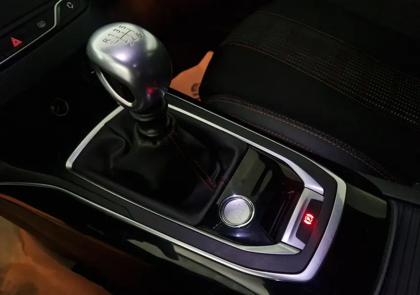 Gros plan sur la console centrale de la Peugeot 308 SW 1.5 BlueHDi 130 GT Line 2019, avec levier de vitesse manuel et bouton démarrage.