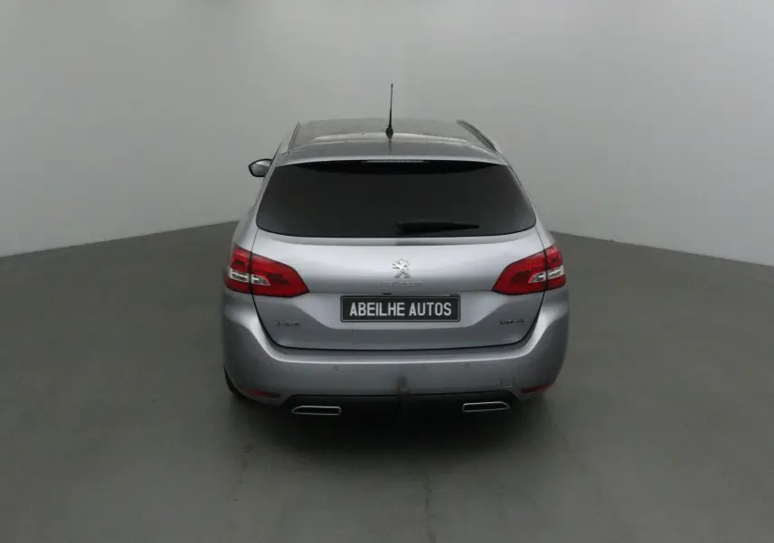 Vue arrière d'une Peugeot 308 SW gris Artense avec vitres teintées et double sortie d'échappement visible.