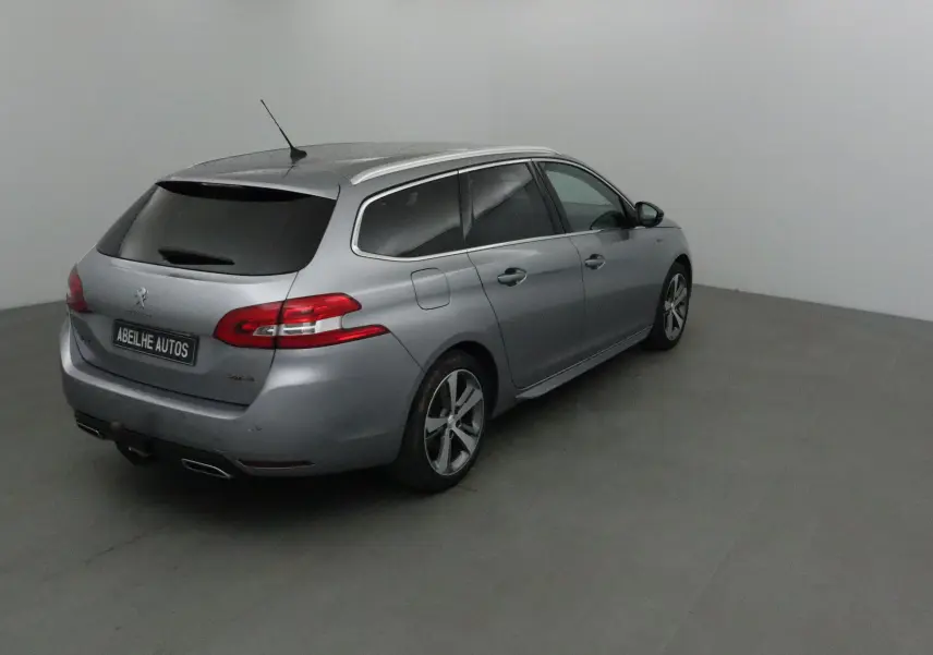 Peugeot 308 SW gris Artense vue 3/4 arrière droit dans un studio, avec vitres teintées et jantes alliage.