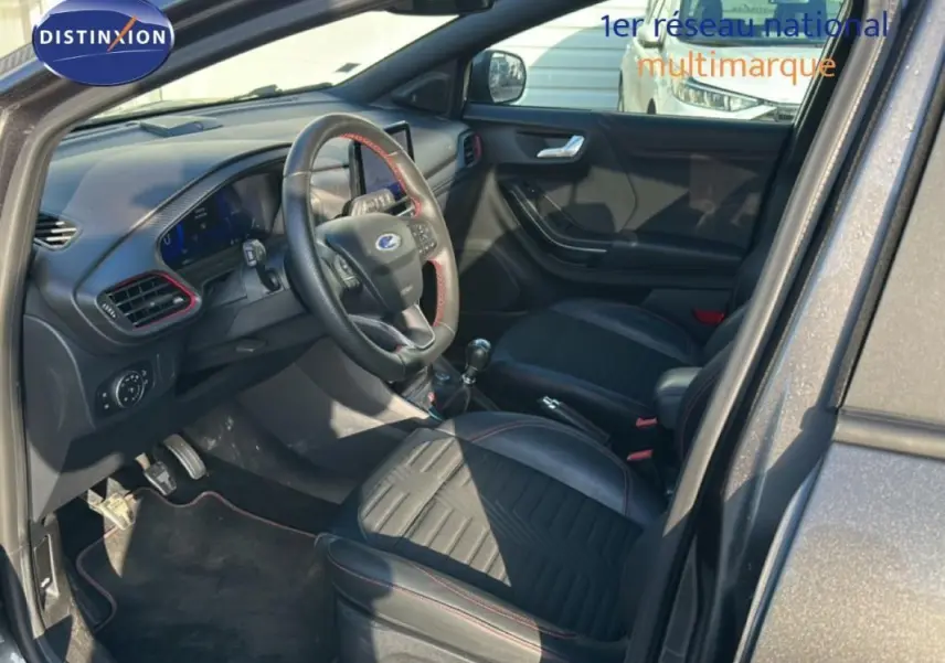 Vue intérieure côté conducteur du Ford Puma gris foncé 2020, avec sièges noirs et volant sport à surpiqûres rouges.