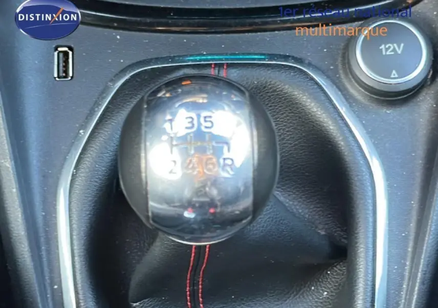 Gros plan sur le levier de vitesses manuel chromé de la Ford Puma gris foncé, avec coutures rouges visibles.