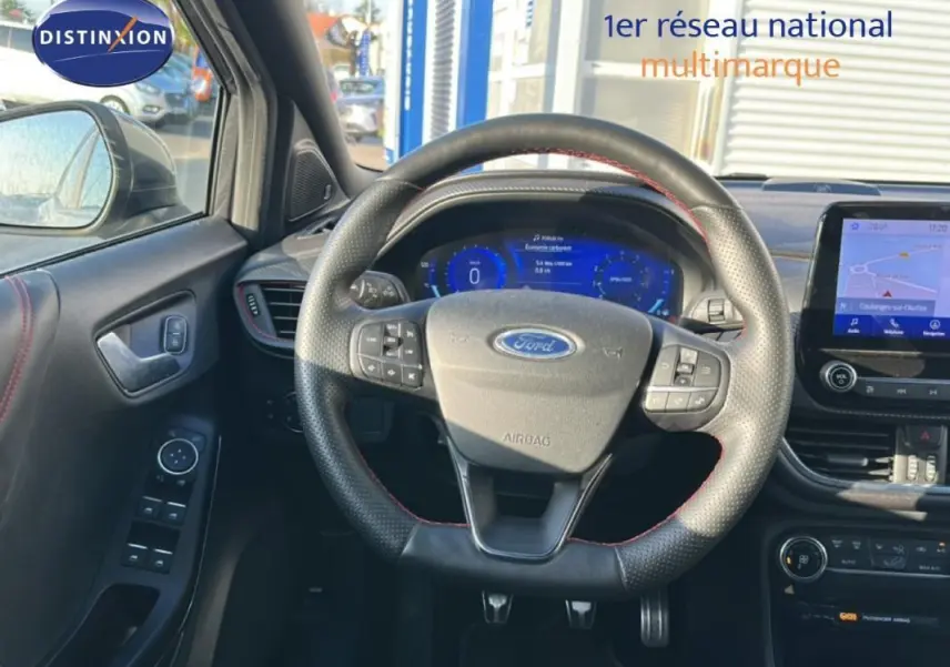 Vue intérieure centrée sur le volant et tableau de bord numérique du Ford Puma gris foncé avec écran tactile GPS.