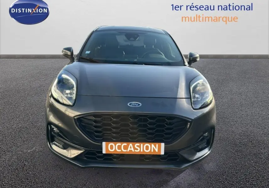 Vue frontale d'une Ford Puma gris foncé avec calandre noire et feux avant allumés sur fond neutre.