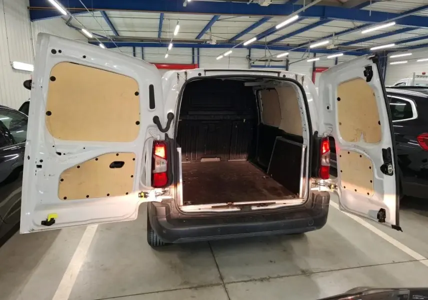 Vue arrière du Peugeot Partner Fourgon blanc 2022 avec portes ouvertes, plancher bois antidérapant et habillage intérieur clair.