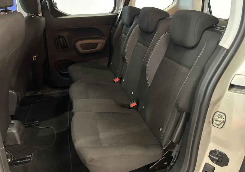 Vue latérale droite de l'intérieur arrière du Peugeot Rifter 2019, sièges tissu noirs avec appuie-têtes et porte gris sable ouvert.