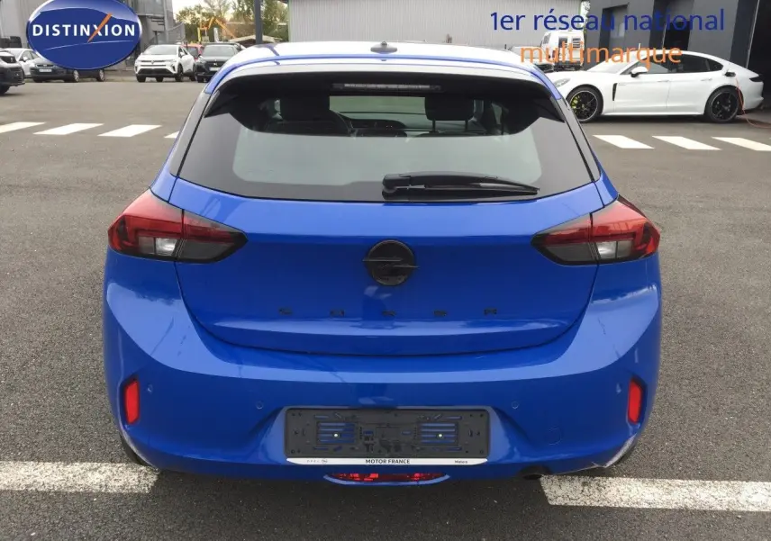 Vue arrière d'une Opel Corsa 2025 bleu voltaik métal avec feux arrière LED et hayon fermé sur parking extérieur.