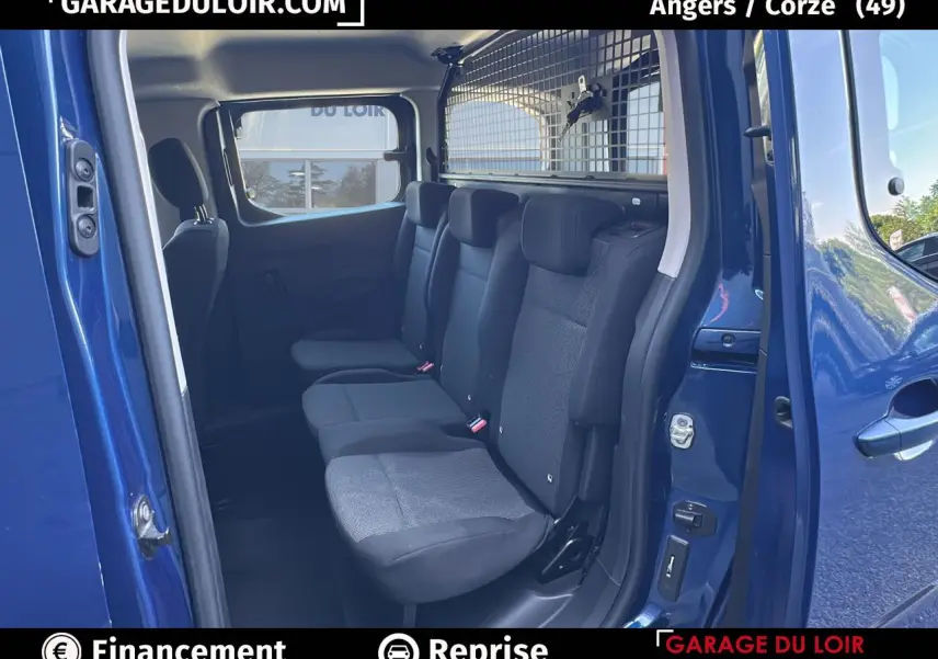 Vue intérieure côté droit sur la banquette arrière noire du Peugeot Rifter bleu avec cloison de séparation métallique.