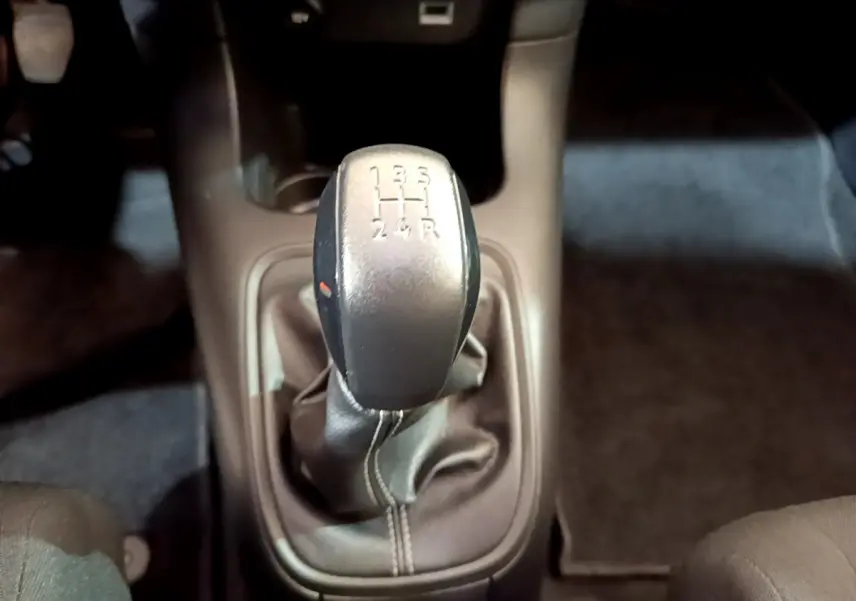 Le levier de vitesses manuel noir de la Citroën C3 blanche, vu de dessus dans l'habitacle.