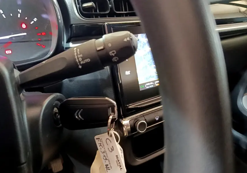Vue rapprochée de l'intérieur de la Citroën C3 blanche 2019, montrant le volant, clé et écran tactile de navigation.