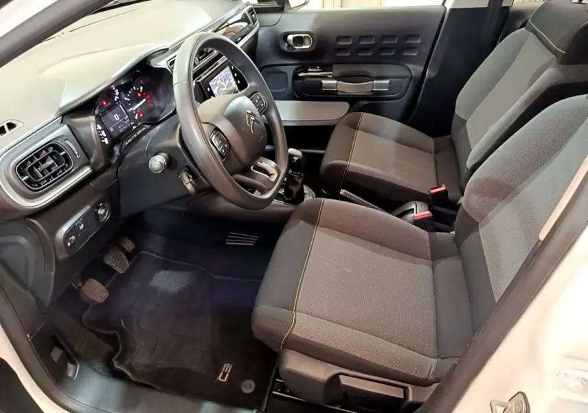 Intérieur avant droit de la Citroën C3 blanche 2019, montrant sièges gris, volant multifonctions et tableau de bord tactile.