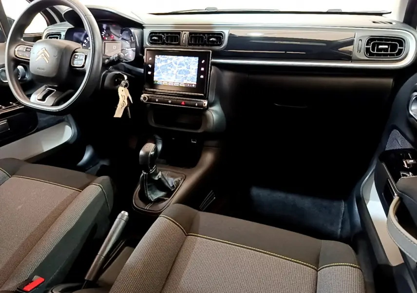 Intérieur avant droit d'une Citroën C3 blanche 2019 avec tableau de bord noir, écran tactile et boîte manuelle.