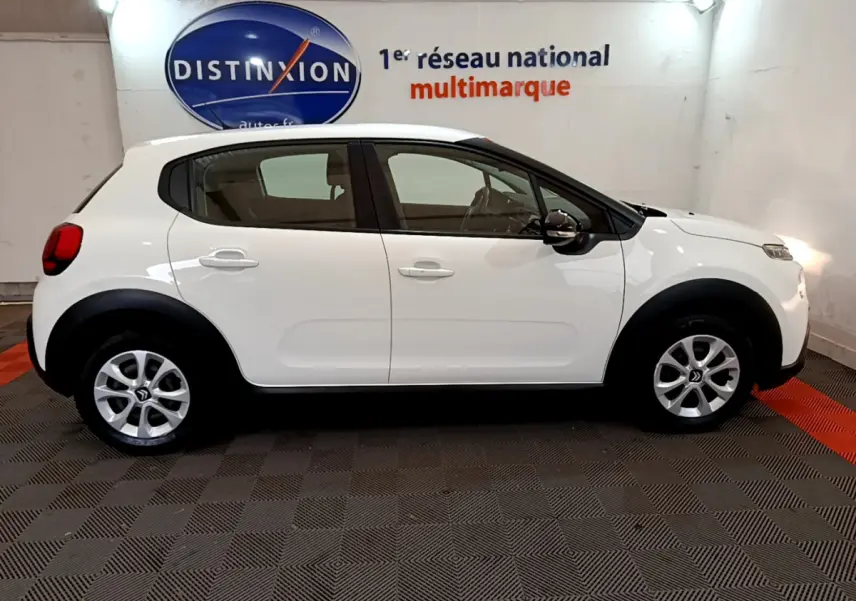 Profil côté droit d'une Citroën C3 blanche 2019 avec protections noires et jantes alliage en showroom.