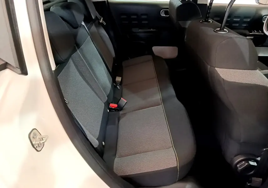 Vue intérieure côté gauche sur la banquette arrière grise d'une Citroën C3 blanche de 2019.