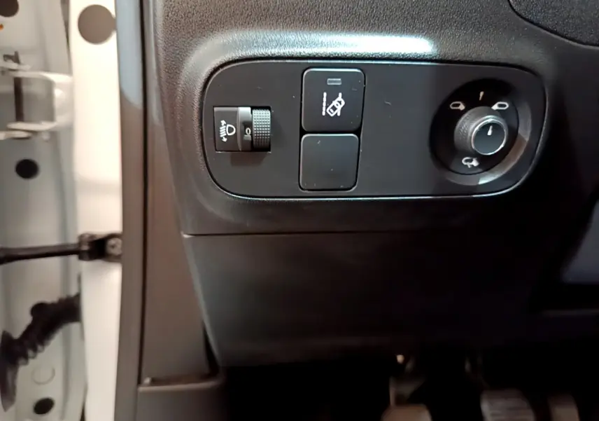 Gros plan sur les commandes d'éclairage et réglage des rétroviseurs côté conducteur d'une Citroën C3 blanche de 2019.