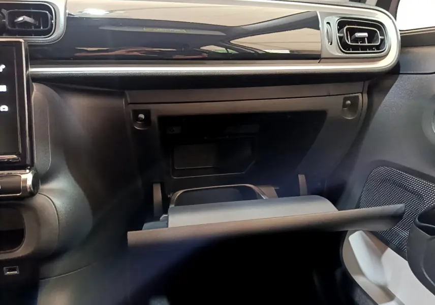 Intérieur de la Citroën C3 blanc, vue du tableau de bord côté passager avec boîte à gants ouverte et finition noire brillante.