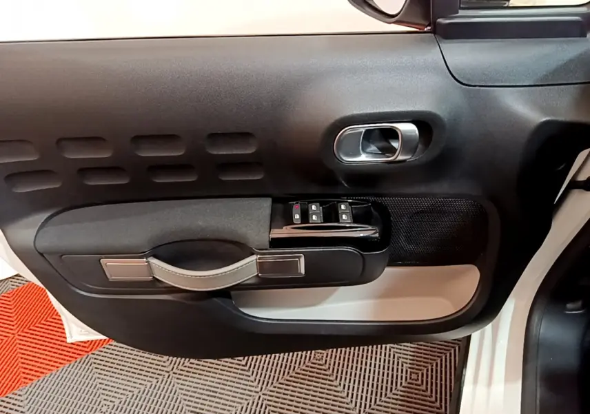Vue rapprochée de la porte avant gauche blanche d'une Citroën C3 2019, avec commandes de vitres et poignée intégrée.