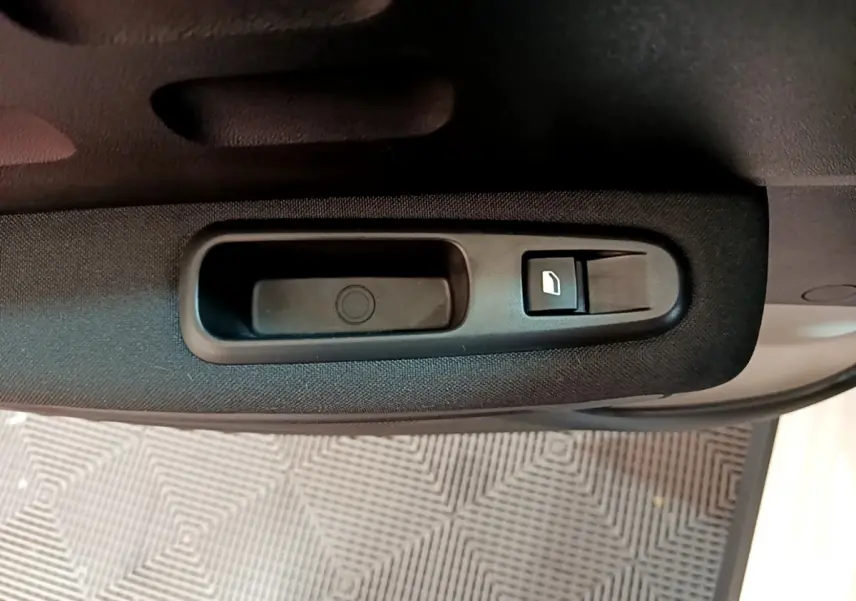 Poignée intérieure noire avec bouton de commande de vitre sur la porte côté gauche d'une Citroën C3 blanche.