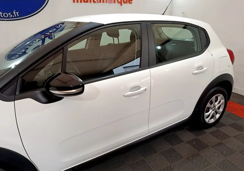 Profil côté gauche d'une Citroën C3 blanche de 2019 avec rétroviseur noir et poignées de porte ton caisse.