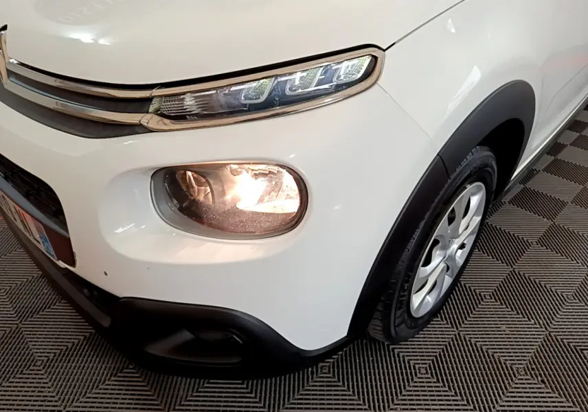 Gros plan sur l'avant droit blanc d'une Citroën C3 2019 avec phares allumés et jante alu visible.