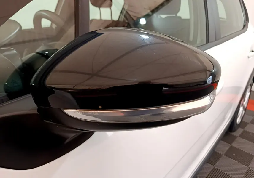 Rétroviseur noir avec clignotant intégré côté gauche d'une Citroën C3 blanche vue de près en intérieur.