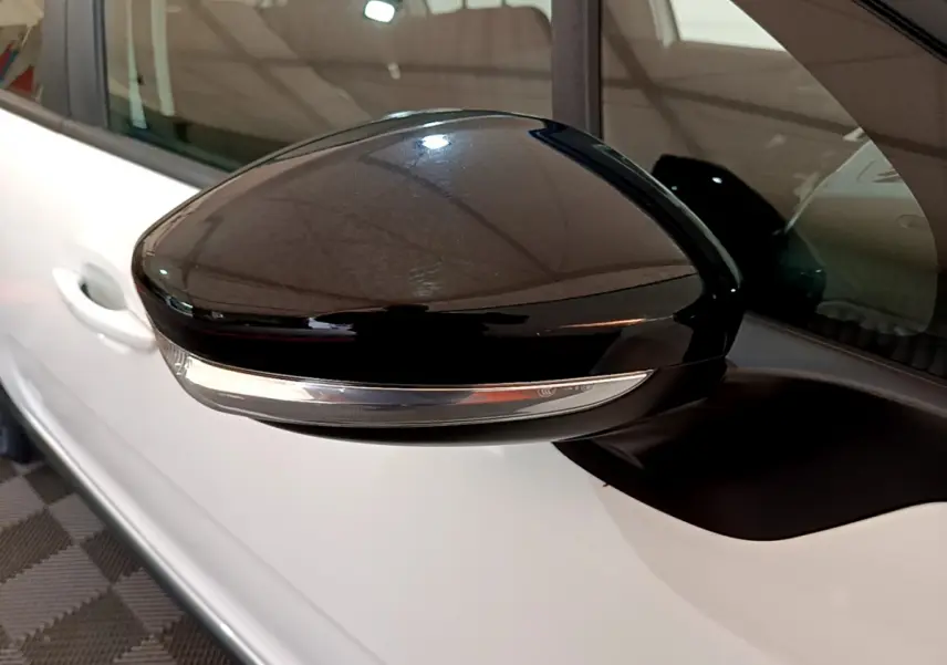 Rétroviseur noir brillant côté gauche d'une Citroën C3 blanche de 2019, avec clignotant intégré.