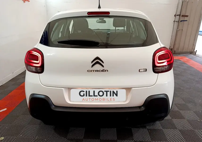 Vue arrière d'une Citroën C3 blanche de 2019 avec feux arrière allumés et logo centré sur le hayon.